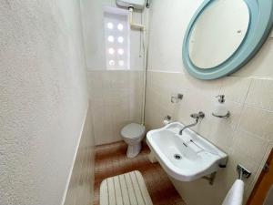 a bathroom with a sink and a mirror and a toilet at Apartman Asta in Jadranovo