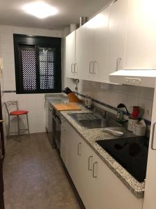 een keuken met witte kasten en een wastafel en een rode kruk bij Maravilloso alojamiento en pleno centro de Dos Hermanas in Dos Hermanas