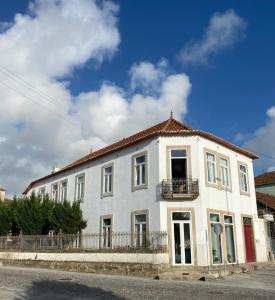 a white building with a balcony on a street at Casa dos Caminhos de Santiago in Mosteiró