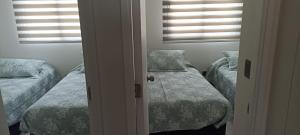 a bedroom with two beds and two windows at departamento avenida del mar in La Serena +19 photos