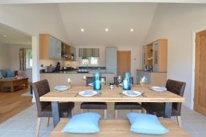 Una mesa de comedor con sillas y una cocina. en Woodland Lodge, Aldeburgh, en Aldeburgh