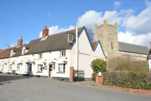 a white house with a black roof on a street at Vesta Cottage, Orford in Orford