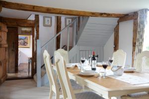 uma sala de jantar com uma mesa de madeira e cadeiras brancas em Wassicks Cottage, Haughley em Haughley