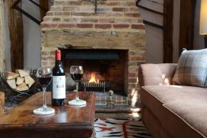 una sala de estar con chimenea y 2 copas de vino en Wassicks Cottage, Haughley en Haughley