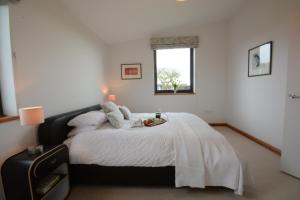 a bedroom with a bed with white sheets and a window at Upper Lodge, Shotley 