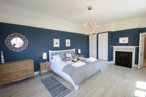 ein blaues Schlafzimmer mit einem Bett und einem Kamin in der Unterkunft Holly Lodge in Aldeburgh