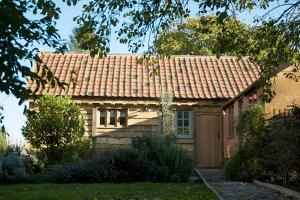 una casa con techo de baldosa en un patio en Chobbs Barn, Eye, en Eye