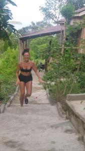 Una mujer en bikini caminando por un camino en Sweet jungle sea view bungalows en Sihanoukville