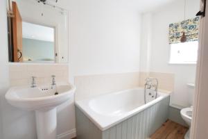 ein weißes Badezimmer mit Waschbecken und Badewanne in der Unterkunft Seawall Cottage, Aldeburgh in Aldeburgh + 14 Fotos