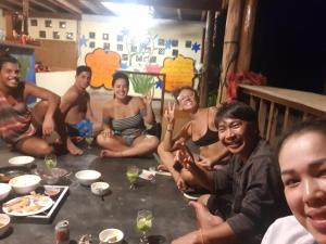 een groep mannen die rond een tafel zitten met eten bij Sweet jungle sea view bungalows in Sihanoukville