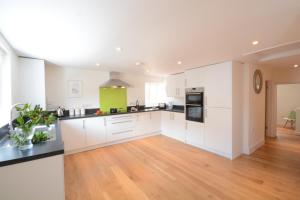 a kitchen with white cabinets and a hardwood floor at Southwold Arms Apartment in Southwold