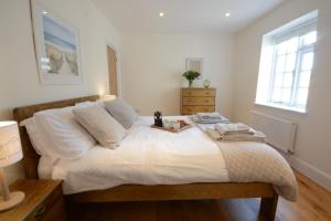a bedroom with a bed with white sheets and a window at Southwold Arms Apartment in Southwold