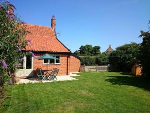 a red brick house with a table and chairs in a yard at 1 Grange Cottages, Westleton in Westleton