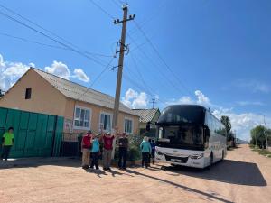 a group of people standing in front of a bus at Guesthouse Gulmira in Bokonbayevo