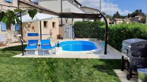 a swimming pool with two blue chairs and a grill at La Fassina in Valdobbiadene