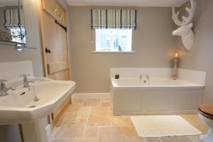 a bathroom with two sinks and a tub and a toilet at Bird Cottage, Burgh in Grundisburgh