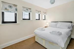 a bedroom with a bed with white sheets and windows at Cool and Chic Duffield Road Apartments in Derby