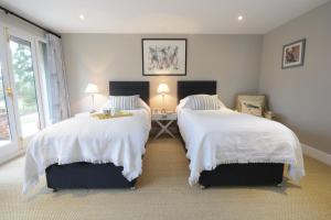 a bedroom with two beds with white comforters at Bird Cottage, Burgh in Grundisburgh