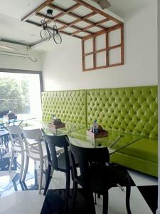 een eetkamer met een groene bank en tafels en stoelen bij VIAN INN in Guwahati