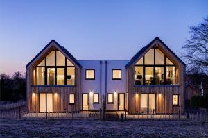 a wooden house with two large windows at night at Rush House, Eastbridge in Westleton