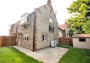 a brick house with a fence and a yard at LOBSTER COTTAGE (Norfolk Costal Cottage) in Langham