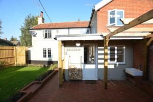 a house with a white door and a patio at Little Turnpike Cottage, Melton in Woodbridge