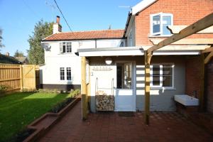a house with a white door and a patio at Little Turnpike Cottage, Melton in Woodbridge