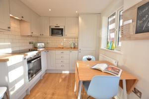 uma cozinha com uma mesa de madeira e uma sala de jantar em Little Turnpike Cottage, Melton em Woodbridge