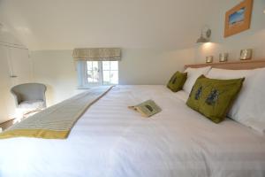 una camera da letto con un grande letto bianco con un libro sopra di Little Turnpike Cottage, Melton a Woodbridge
