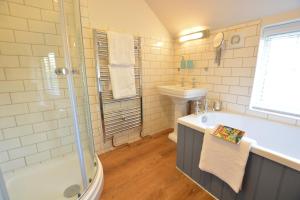 a bathroom with a tub and a sink and a shower at Little Turnpike Cottage, Melton in Woodbridge +16 photos