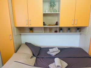a bed in a room with yellow cabinets and towels at Apartman SkiBeg, Vlašić in Vlasic