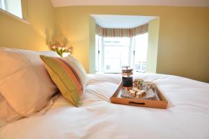 a tray with a candle on a white bed at Harriet's Cottage, Southwold in Southwold