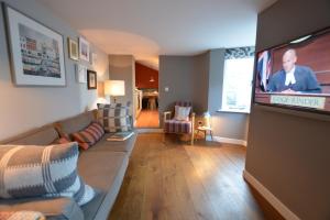 a living room with a couch and a flat screen tv at Harriet's Cottage, Southwold in Southwold