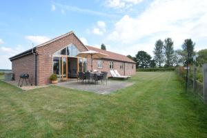 a brick house with a patio and an umbrella at The Mulberry, nr Bungay in Bungay