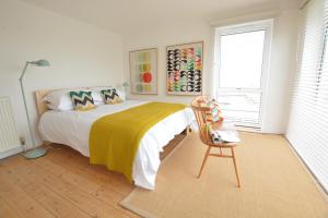 een slaapkamer met een bed met een gele deken en een stoel bij Aldeburgh Lodge Gardens in Aldeburgh