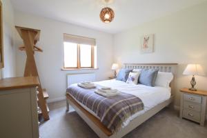 a bedroom with a bed with white sheets and blue pillows at The Mulberry, nr Bungay in Bungay