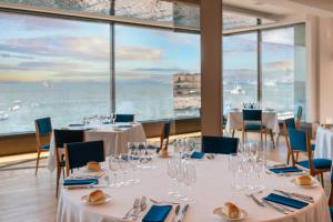 um restaurante com mesas e cadeiras com vista para o oceano em Hotel Royal Continental em Nápoles