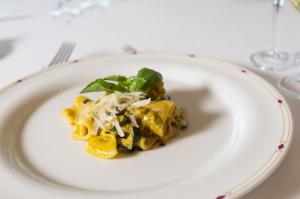a plate of food with pasta and greens on a table at Hotel Royal Continental in Naples