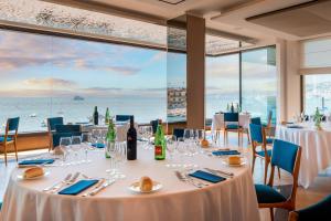 a dining room with tables and chairs with a view of the ocean at Hotel Royal Continental in Naples