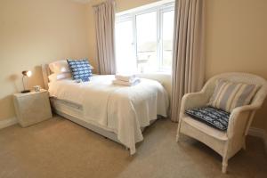 a bedroom with a bed and a chair and a window at Meadowsweet, Blythburgh in Blythburgh