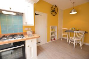une cuisine avec des murs jaunes et une table avec des chaises dans l'établissement Alinka, Aldeburgh, à Aldeburgh