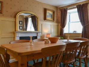 a dining room with a wooden table and a mirror at Old Saddlers Cottage in Ireby