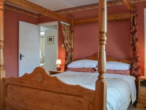 a bedroom with a four poster bed and a mirror at Old Saddlers Cottage in Ireby