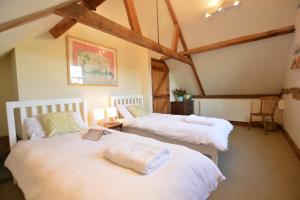 two beds in a room with wooden beams at Wheelwright's Barn in Halesworth