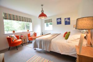 a bedroom with a bed and two orange chairs at Field Edge, Tunstall in Tunstall