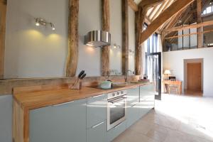 a kitchen with white cabinets and a wooden counter top at Manor House Barn, Peasenhall in Peasenhall