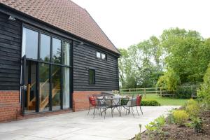 a patio with a table and chairs in front of a house at Manor House Barn, Peasenhall in Peasenhall