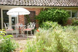 a patio with a table and chairs and an umbrella at The Nookery at Snape Hall in Snape