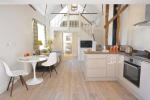 eine Küche mit weißen Schränken sowie einem Tisch und Stühlen in der Unterkunft Carriage House, Bruisyard in Framlingham