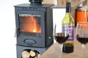 a stove with two glasses of wine and a bottle of wine at Carriage House, Bruisyard in Framlingham